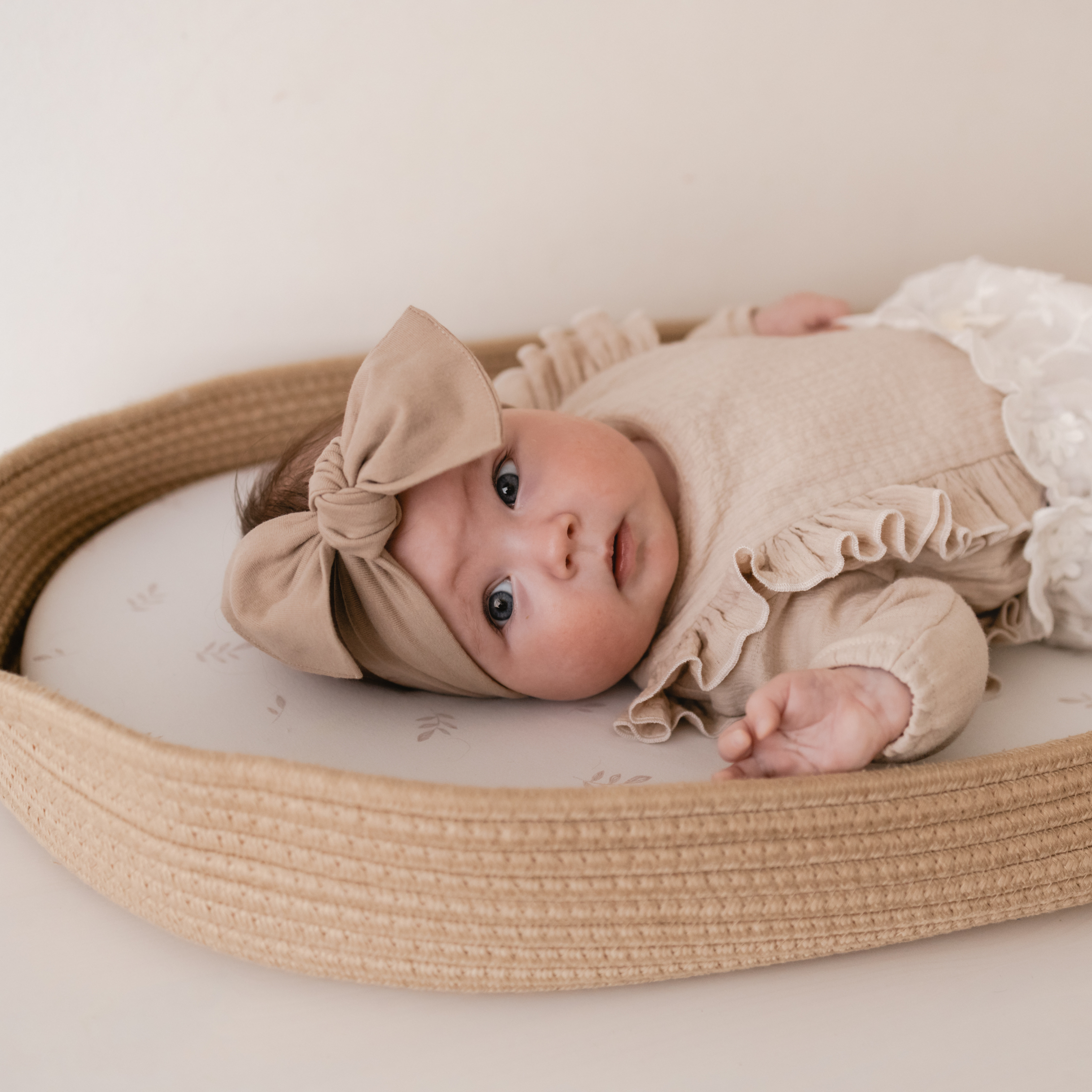 Een baby in de Little Moon Verschoonmand Natural Sand en het Floating Leaf matrashoesje